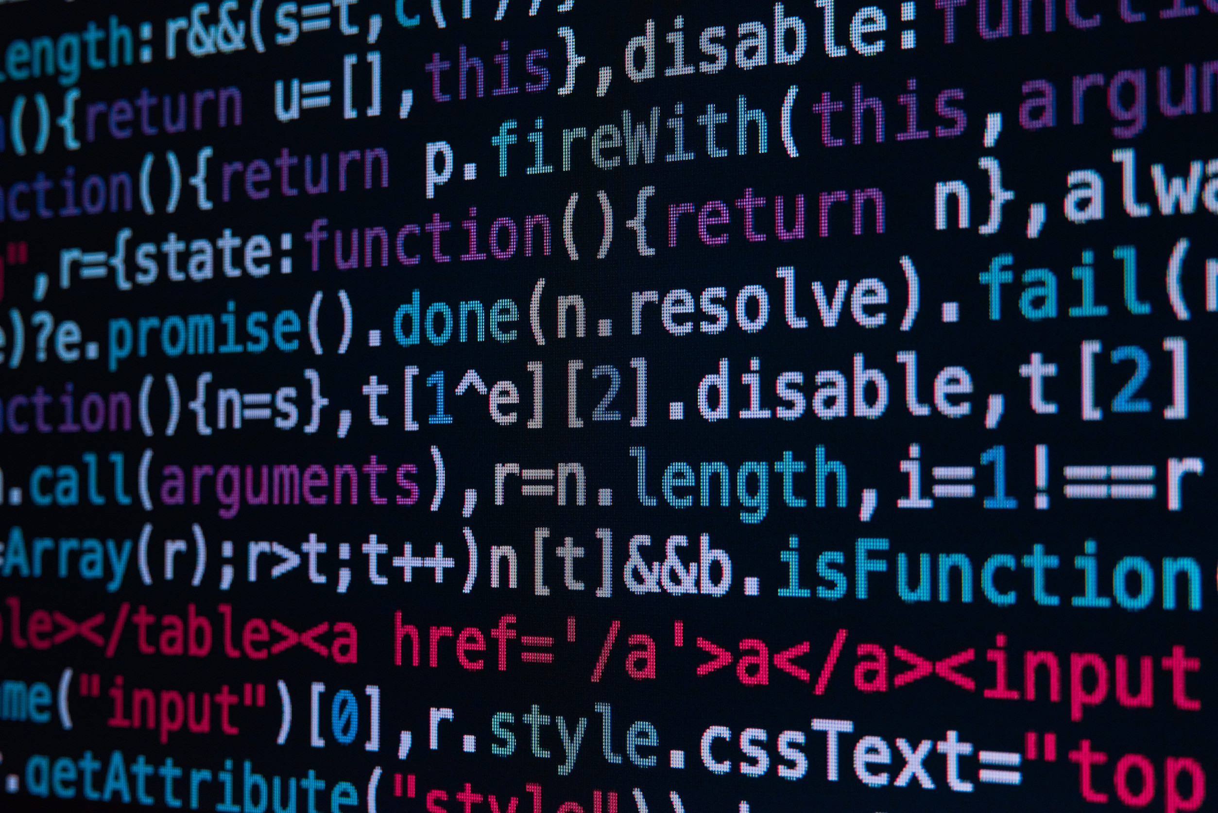 Close-up of colorful programming code on a dark screen, showing HTML/CSS/JavaScript syntax with highlighted keywords and tags